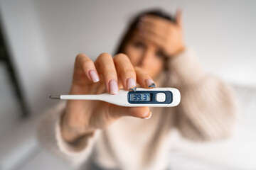 Unhealthy woman with a high fever showing thermometer with high body temperature 39.3