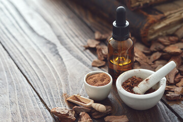 Pine bark, tincture or oil bottle, mortars of powdered pine bark and old books on background. Copy space for text.