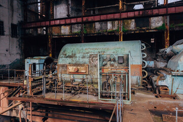 Rusty turbine generator. Abandoned destroyed by war and overgrown by plants and moss machinery of Tkvarcheli Tquarchal power plant, Abkhazia, Georgia