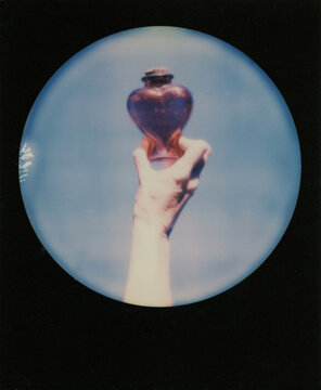Polaroid scan of a hand holding a heart shaped bottle