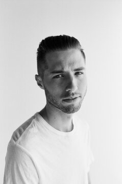 Head shot portrait of young adult male with short hair wearing white t-shirt in studio