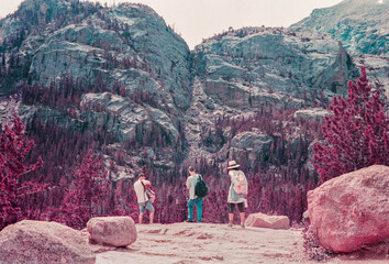 Three friends taking a break from hiking and reaching into their backpacks