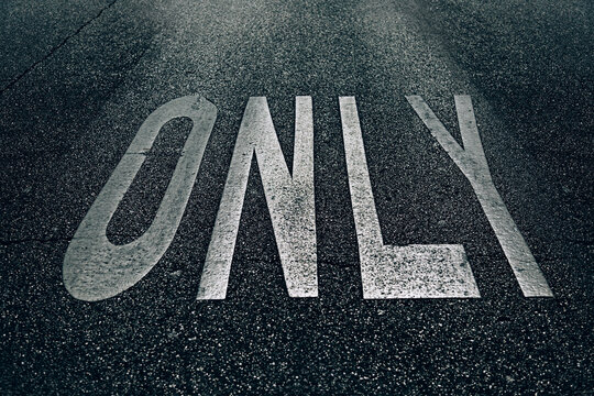 Grungy ONLY road sign painted in the asphalt
