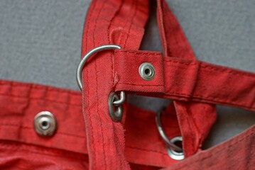  metal rivet and carabiner in a red cloth harnes on a gray table