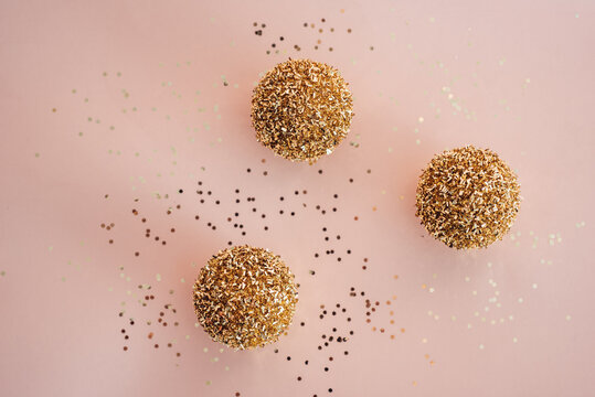 Golden Christmas balls and confetti on a pink background
