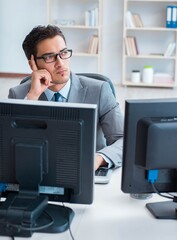 Businessman sitting in front of many screens