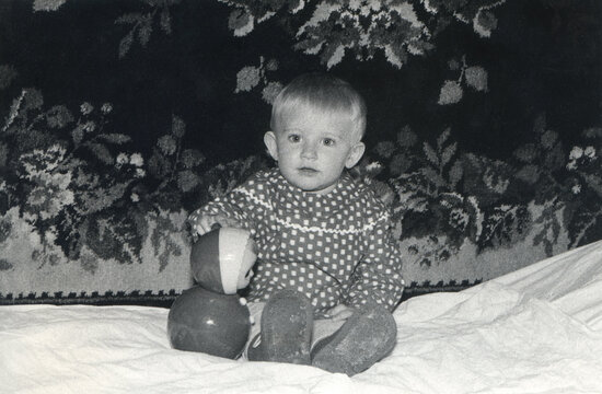 Vintage monochrome photo of little lovely girl sitting on the bed