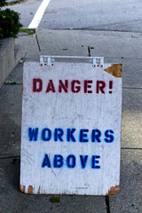View of sign "Danger! Workers above" on sidewalk in Vancouver, Canada.