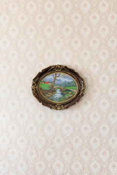 Handmade framed tapestry with landscapes hanging on wall with vintage wallpaper