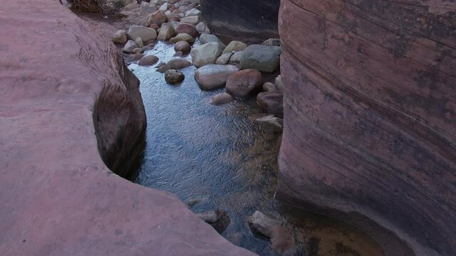 Riverbed in Utah desert slot canyon with rocks water and ice in the path carved into the sandstone.