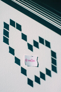Note saying #metoo inside a heart shadow on a wall