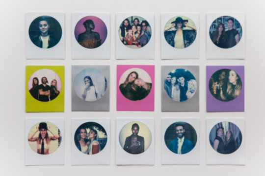 Defocussed photo of fifteen round polaroid prints arranged in three rows of five.
