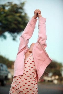 Young girl in pink with hands up in joy