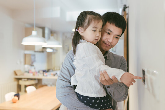 Asian Father And Kid Adjusting The Thermostat At Home