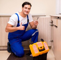 Young repairman working at the kitchen