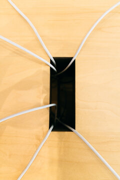 Computer cables coming out of a hole on a desk