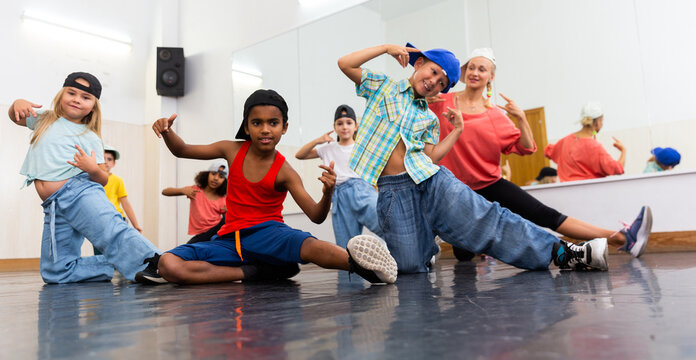 Positive girls and boys with female teacher posing in dance studio during hip hop class
