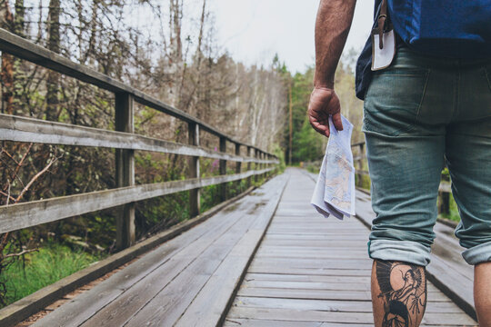 Man holding a map on a wooden bridge in the forrest