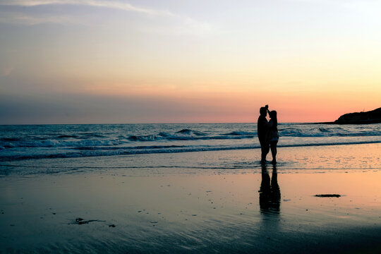 Silhouette of a couple embracing at sunset on the beach in Santa Cruz