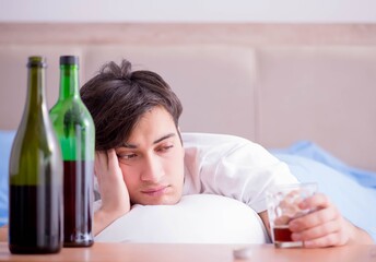 Man alcoholic drinking in bed going through break up depression