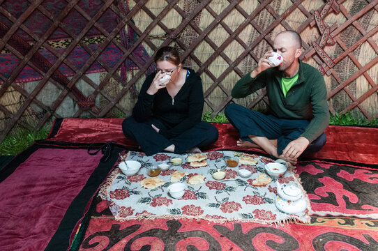 Male and female traveller's eating typical Kyrgyzstan food inside a yurt, Kyrgyzstan.