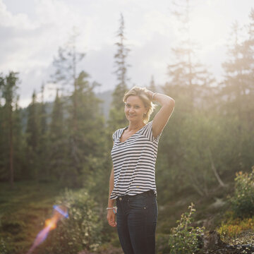Young woman with striped sweater in the Norwegian forest at sunset