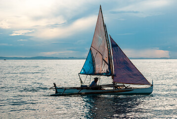 Fototapeta premium Small home made sail cruising during a sunset