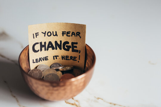 Copper bowl with coins with sign "If you fear change, leave it here"