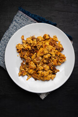 Scrambled eggs with chorizo for breakfast on dark background. Mexican food