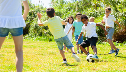 Obraz premium Group of happy kids are running and playing football in park at summer day