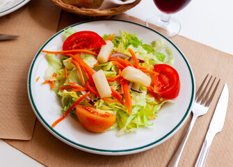 Mediterranean vegeterian salad served with carrot and onion on wooden table