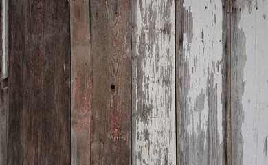 Rustic wood siding with peeling white paint on a shed