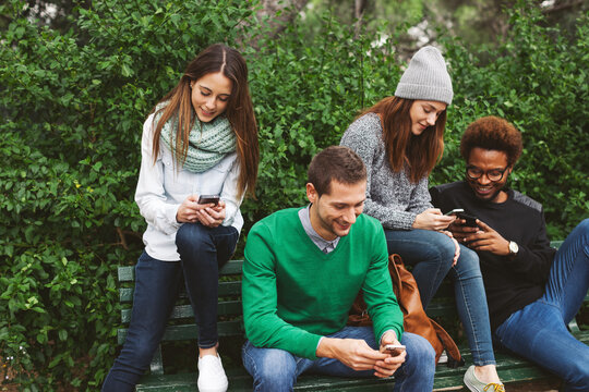 Group of friends hanging out chatting with their smartphones.