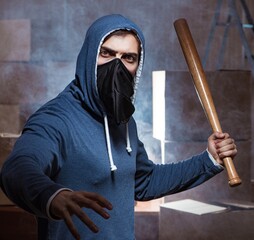 Hooligan with bat in dark room
