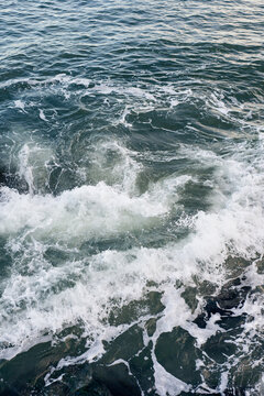 Waves breaking on underwater rocks, creating a small water vortex
