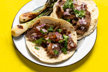 Grilled beef steak tacos on yellow background. Mexican food