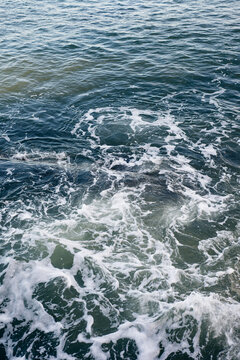 Waves breaking on underwater rocks, creating a small water vortex