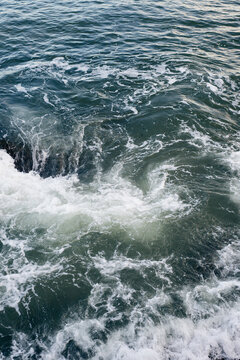 Waves breaking on underwater rocks, creating a small water vortex