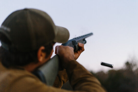 Person aiming gun at target and shooting shotgun