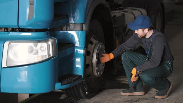 Technical engineer checking tire of a truck. Car repairment, service.