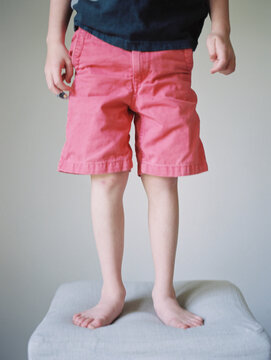 little boy standing on a stool in shorts