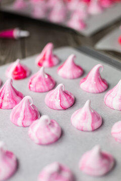 Pink meringue kisses on baking sheet