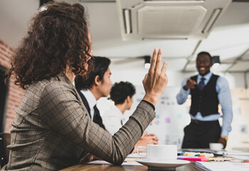 selective focus on the finger. Businesswoman Raise your finger to inquire from the meeting leader African American about business a smiling and fun in meetings At the meeting room in the office.