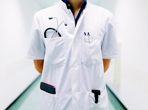 Close up of a doctor in a white suit with a beeper and a stethoscope in a hospital