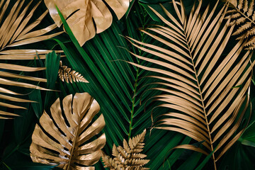 Creative nature background. Gold and green tropical Monstera and palm leaves. Minimal summer abstract jungle or forest pattern. - obrazy, fototapety, plakaty