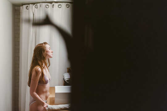 Young Woman Wearing Lingerie Looking in the Bathroom Mirror