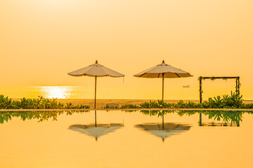Umbrella and chair around outdoor swimming pool in hotel resort