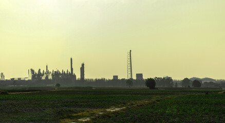 Fototapeta na wymiar Shadow of industrail factory plant with green fields in the morning