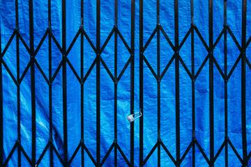 Locked metal security gate over blue tarp