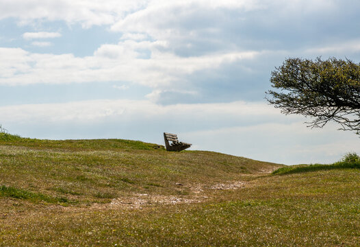 A bench on top of a hill in an open space.